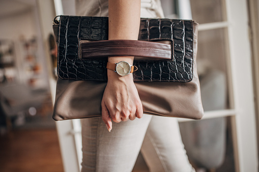 Unrecognizable elegant woman holding modern leather purse.