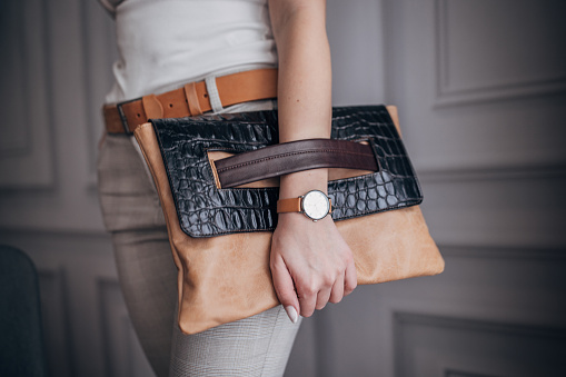 Unrecognizable elegant woman holding modern leather purse.