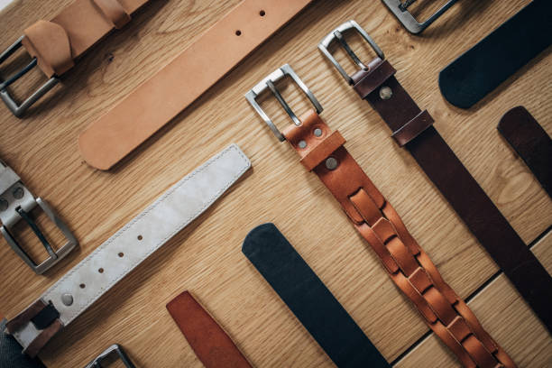 Variety of modern leather belts on wooden table.