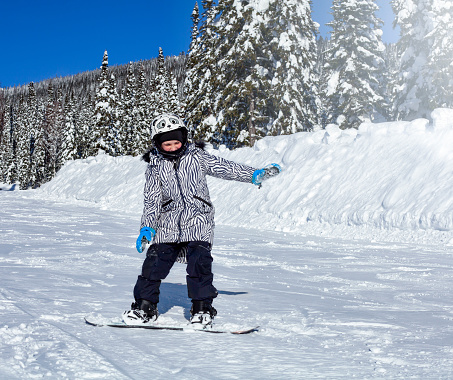 child rides a snowboard on a mountain slope