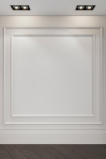 Empty, unfurnished, classic, elegant interior with a white French-style, antique wall background with moldings (frame) and copy space,  ceiling reflector built-in lights on a hardwood herringbone hardwood floor.  A white empty frame or space for a painting/art object presentation. 3D rendered image.