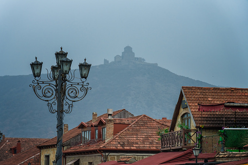 Red rooftops and lantern with Jvari Monastery on background. Mtskheta, Georgia