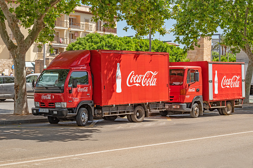 A red Coca Cola delivery vehicle in Alcudia, Majorca. Coca Cola was invented in the late 19th century by John Stith Pemberton in Atlanta, Georgia.