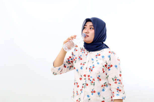 istock Asian muslim woman standing while drinking mineral water. Isolated on white background 1461349724
