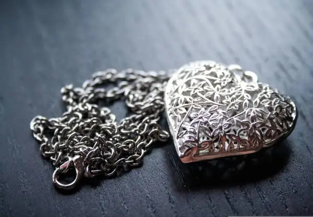 silver necklace in the shape of love on a wooden table