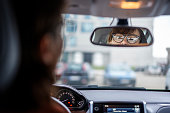 Adult attractive caucasian businesswoman in glasses looking in the rearview mirror while sitting at the wheel of a car