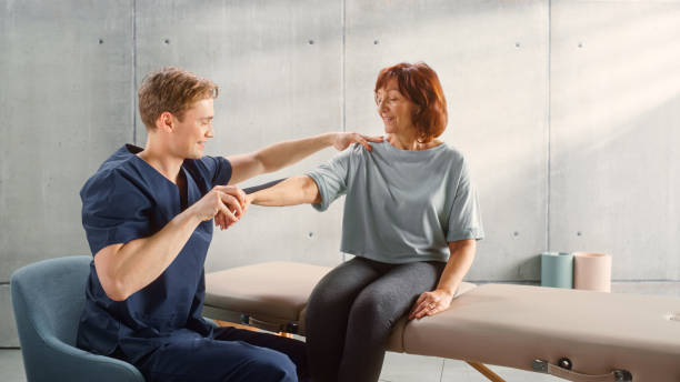 istock Professional Sport Physiotherapy Specialist Stretching and Working on Specific Muscles, Shoulder Joints with Elderly Woman. MIddle Aged Female Recovering from Serious Injury, Undergoing Rehabilitation 1461352834