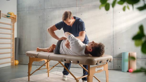 sportsman patient undergoing physical therapy in clinic to recover from surgery and increase mobility. physiotherapist works on specific muscle groups or joints to rehabilitate from injury. - alternatieve geneeskundige fotos stockfoto's en -beelden