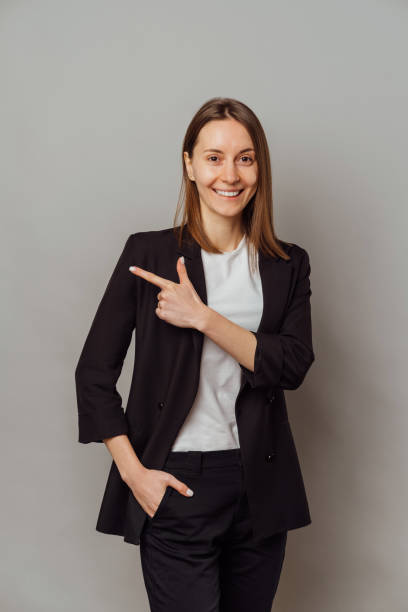 istock Cheerful young confident woman wearing a black jacket is pointing aside. 1461352967