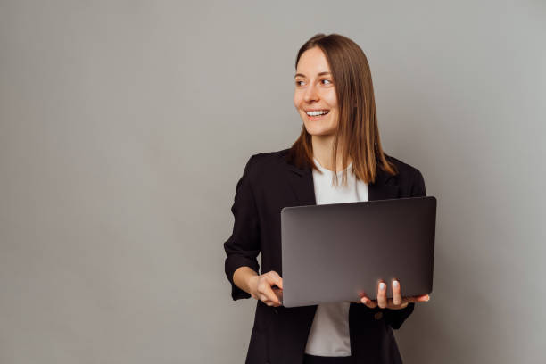 istock Cheerful woman holding an open laptop is looking aside at some copy space. 1461353015