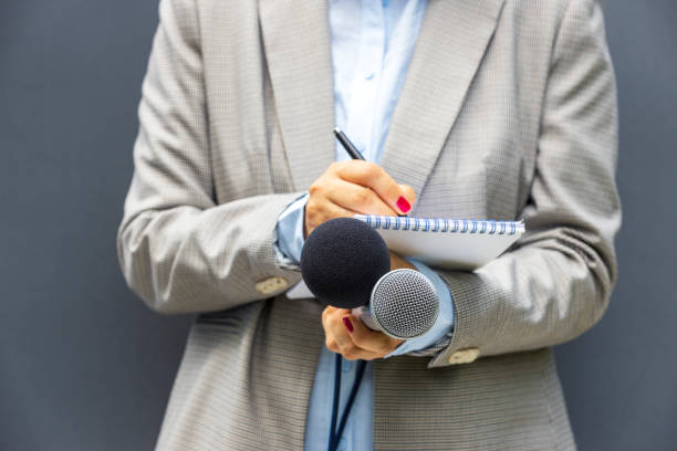 istock Correspondent or reporter at media event, holding microphone, writing notes. Journalism concept. 1461353747