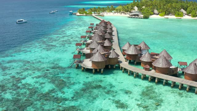 Overwater villas in tropical lagoon of Moorea Island with coral reef. Aerial drone view.