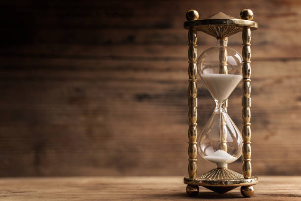 Hourglass on the wooden table with a wooden background Golden hourglass on the wooden table with a wooden background half past stock pictures, royalty-free photos & images