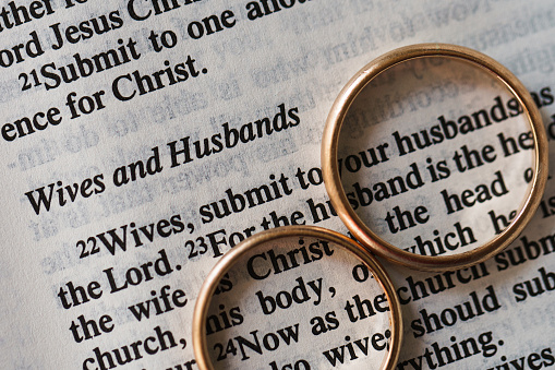 Closeup of two golden wedding rings and opened pages of holy bible represents the concept of marriage and the love between two Christians