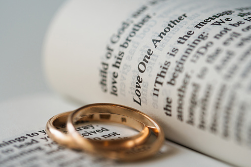 Two golden wedding rings and opened pages of holy bible represents the concept of marriage and the love between two Christians