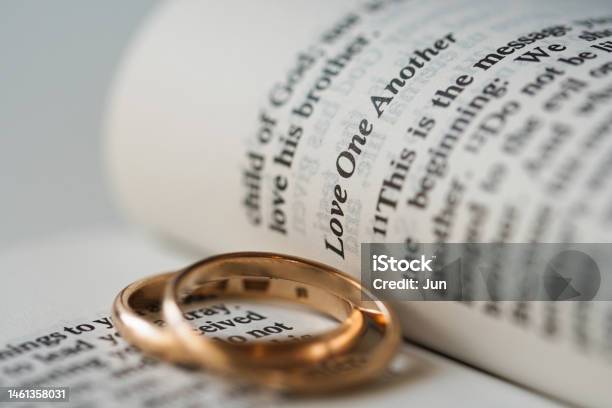 Two Golden Wedding Rings And Opened Pages Of Holy Bible Represents The Concept Of Marriage And The Love Between Two Christians Stock Photo - Download Image Now