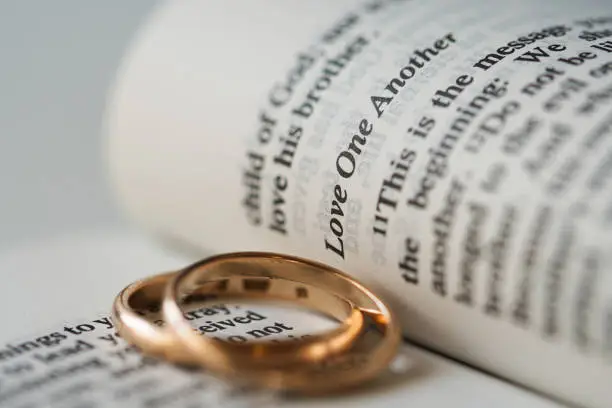 Photo of Two golden wedding rings and opened pages of holy bible represents the concept of marriage and the love between two Christians