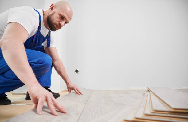 Bearded man installing laminate wood floor in apartment. stock photo