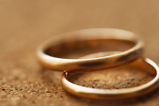 Macro of two wedding rings on a cork table background with shallow DOF