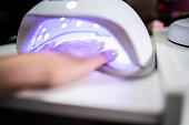 Woman's hand inside UV lamp for nails at a beauty salon