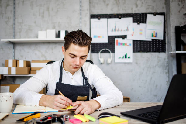istock Smiling young man writing in notebook notes for his small business progress 1461362703