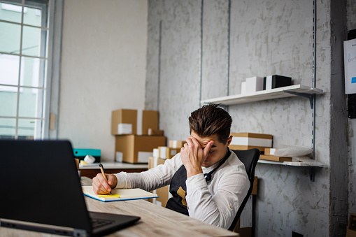 Worried man holds head while works in online store