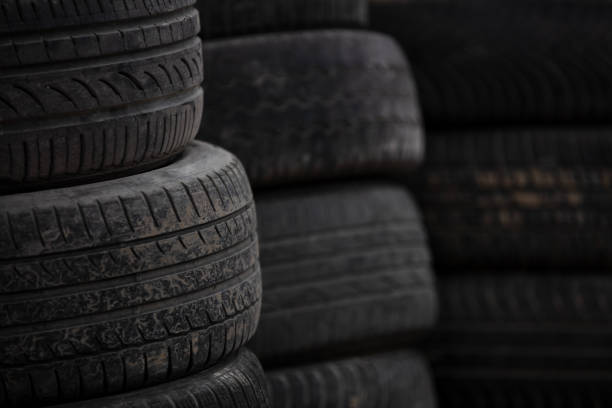 muddy and worn old car tyre over each other waiting in garage depot for recycling