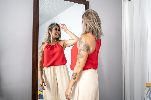 Mature woman looking at herself in the mirror at home