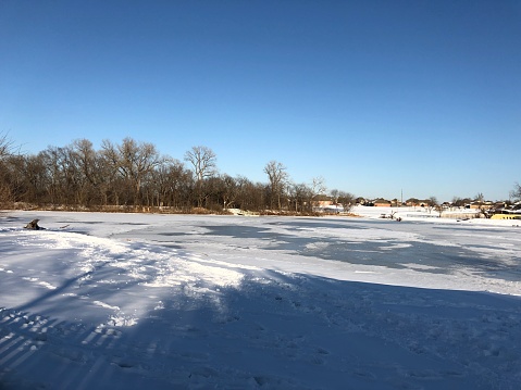 Snow-covered ground with the pond frozen in winter