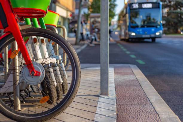 noleggio biciclette e scooter parcheggiati sul marciapiede. sullo sfondo autobus sulla strada - wheel cycling nobody outdoors foto e immagini stock