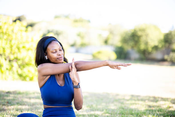 istock Woman sitting on grass in park stretching arms 1461373242