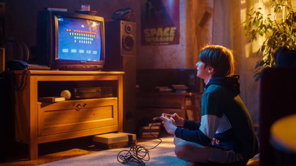 istock Nostalgic Childhood Concept: Young Boy Playing Old-School Arcade Space Shooter Video Game on a Retro TV Set at Home in His Room with Period-Correct Interior. Successful Kid Passes the Level. 1461375192