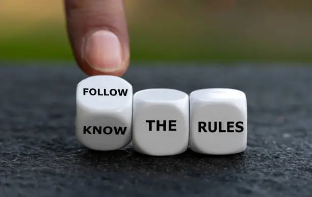 Photo of Hand turns dice and changes the expression 'know the rules'. to 'follow the rules'.