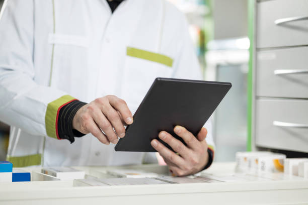 istock Mature pharmacist holding a tablet in drugstore 1461376748
