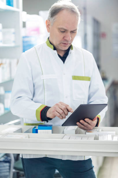 istock Mature pharmacist holding a tablet in drugstore 1461376773