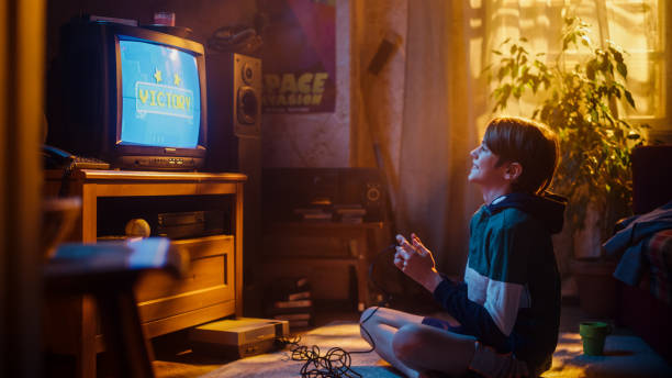 istock Young Boy Playing Eighties 2D Arcade Space Shooter Game on a Gaming Console at Home in His Room with Old-School Interior. Child Successfully Wins Level. Nostalgic Retro Childhood Concept. 1461376912