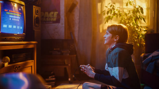istock Young Boy Playing Eighties 2D Arcade Space Shooter Video Game on a Gaming Console at Home in His Room with Old-School Interior. Child Successfully Wins Level. Nostalgic Retro Childhood Concept. 1461376960