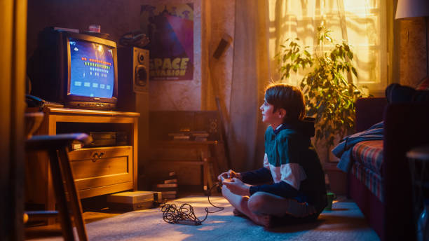 istock Young Boy Playing Eighties Eight Bit Arcade Space Shooter Video Game on a Console at Home in His Vintage Room with Old-School Interior. Child Successfully Wins the Level. Nostalgic Retro Childhood. 1461377046
