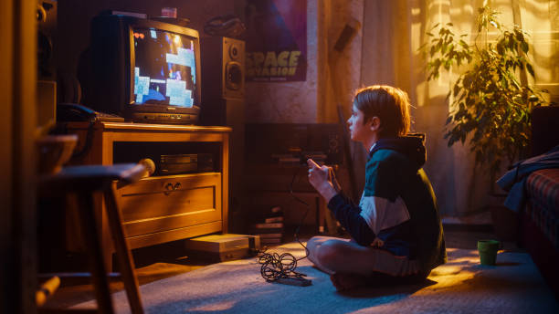 istock Young Boy Playing Eighties Eight Bit Arcade Video Game on a Console at Home in His Room with Old-School Interior. Child Successfully Wins the Level. Nostalgic Childhood Concept. 1461377102