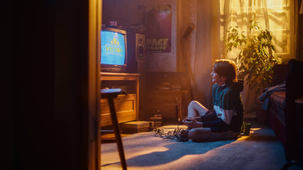 istock Young Boy Playing Eighties Eight Bit Arcade Video Game on a Console at Home in His Room with Old-School Interior. Child Successfully Wins the Level. Nostalgic Retro Childhood Concept. 1461377123