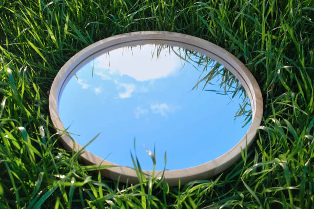istock Cloudy Blue Sky Reflection in Round Wood Mirror on Summer Field with Green Grass. Nature Concept. Earth Day. Save Environment. Peace. Ecology Protection. Climate Change, Global Warming Effect Problem 1461377621