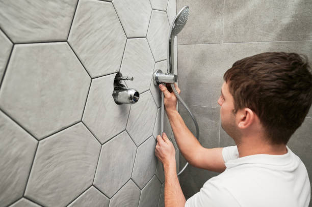 istock Male plumber installing bath showerhead in bathroom. 1461380649