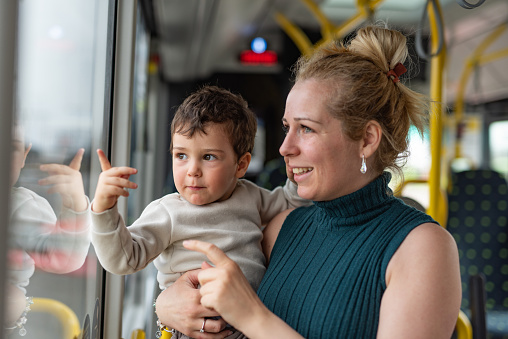 Happy mother and son traveling by bus and looking through window