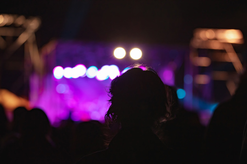Silhouettes of concert crowd with stage lights