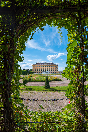 Vienna, Austria - August 12, 2022: Back view of the famous Schonbrunn palace in Austria, seen from a public accessible garden on a sunny day with blue sky and contrasty clouds. Austrian landmark view and its capital city skyline