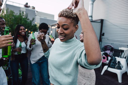 Woman dancing on a rooftop party with friends.