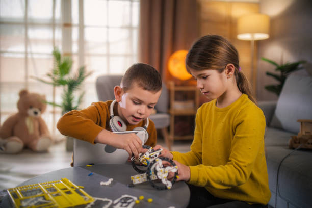 kids making diy robot by looking from digital tablet at home