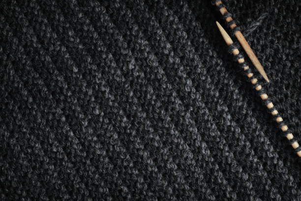 istock Striped knitted fabric and wooden needles. Dark knitted texture background. 1461392708