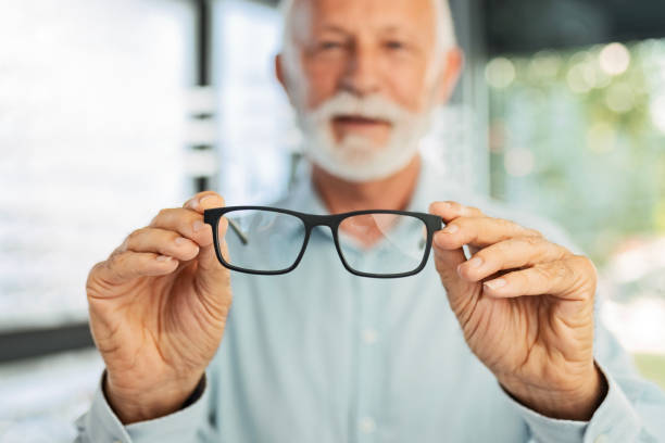 istock Senior man holding eyeglasses looking at camera in optic store 1461409622