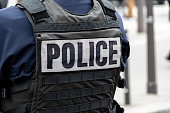 Close-up 'POLICE' marking written on the back of a bulletproof vest worn by a French police officer
